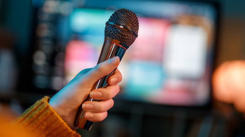 women holding a mic in front of a tv