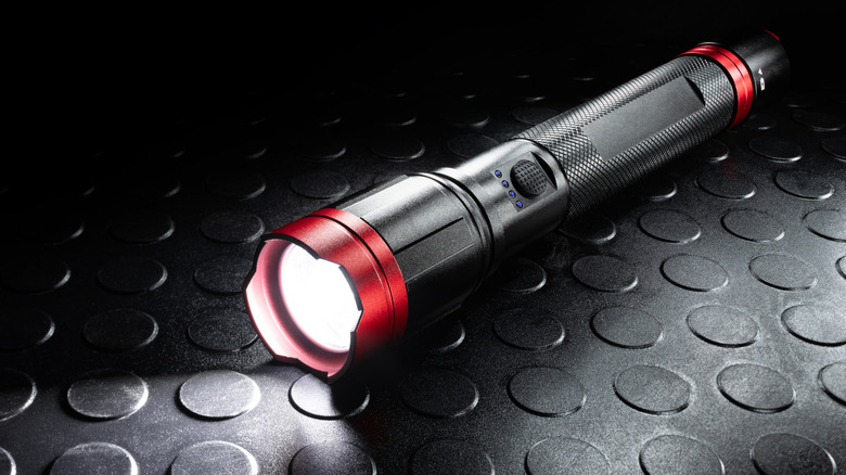 A LED flashlight, activated, against a black backdrop.
