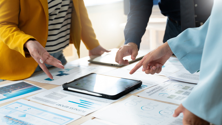 Group of people brainstorming ideas on a tablet