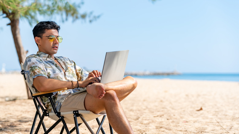 Man sitting at the beach with a laptop