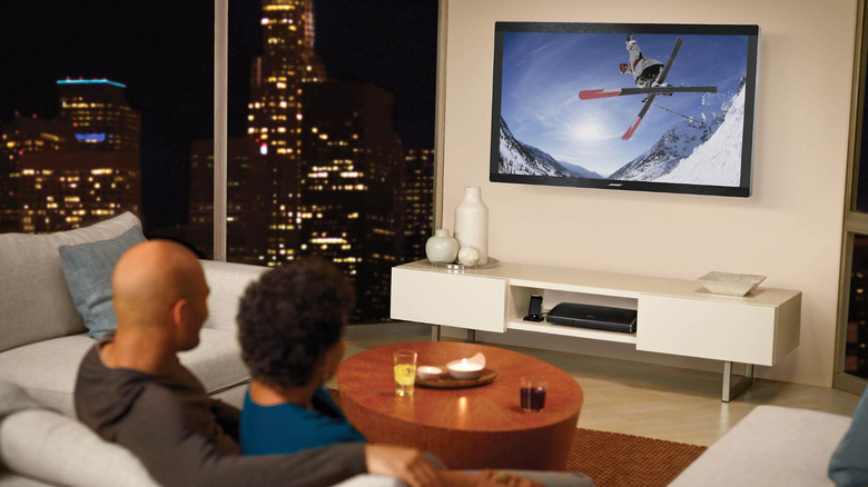 A couple watches TV on the Bose VideoWave II Entertainment System