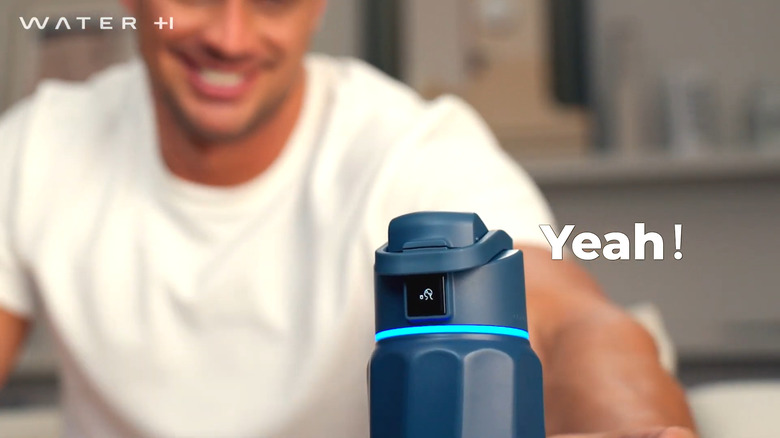 Man reaching for WaterH Boost Smart Water Bottle on table
