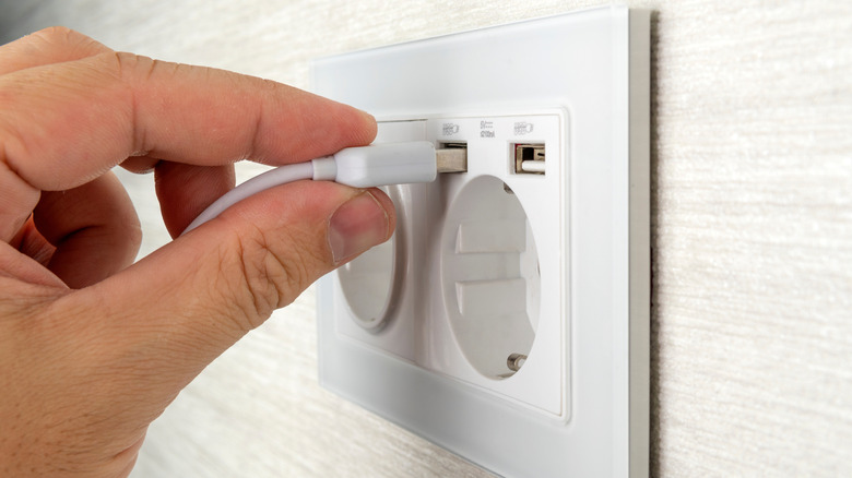 hand plugging in a USB cable to a power adapter