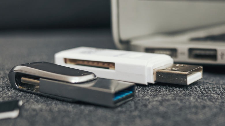 A laptop with two flash drives placed next to it