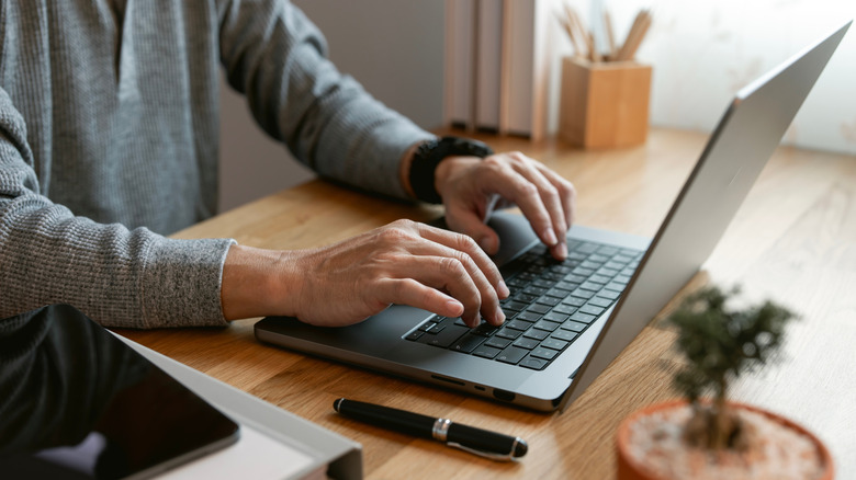 Man typing on a laptop at a desk