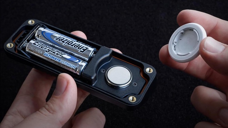 Close-up of a person putting an AirTag in the Elevation Lab AirTag Extended Battery