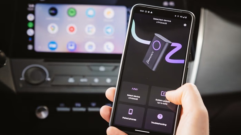 A person using the AAWireless on the phone with a car head unit running Android Auto
