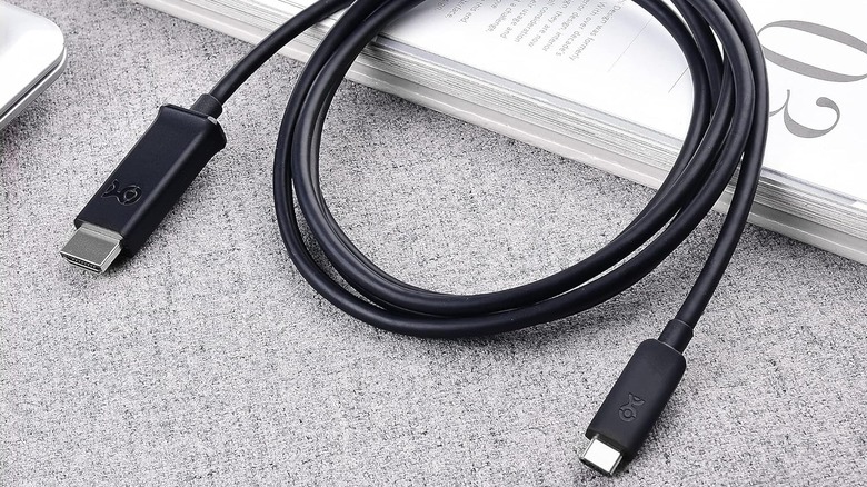 The Cable Matters Unidirectional USB-C to HDMI Cable placed on a book with part of a textured surface