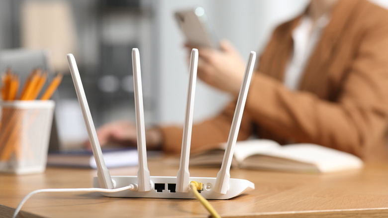 A close up shot of a router with a person in the background on their phone