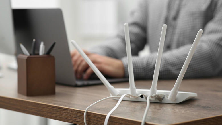 A close up shot of a router with a person in the background on their phone