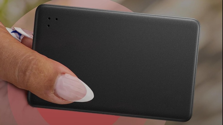 A person holding a Life360 Tile Slim Tracker.