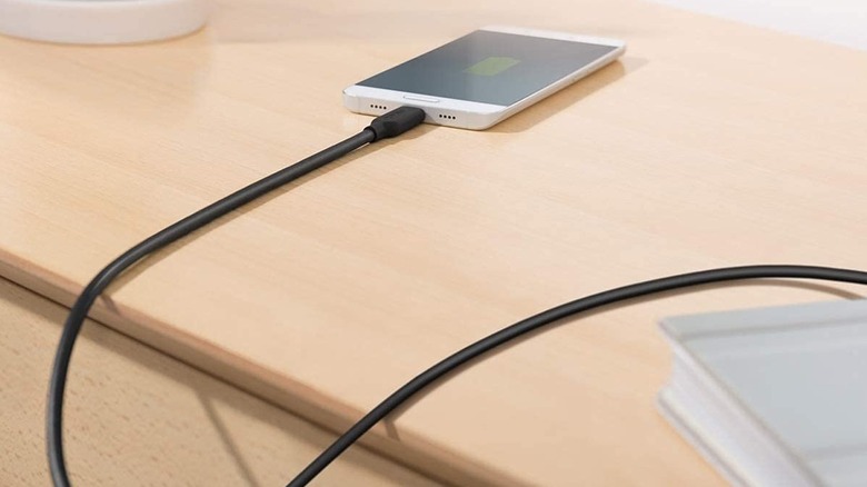 A phone on a wooden desk connecte to the Anker Powerline II USB-C to USB-C cable