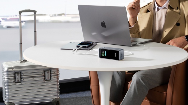 Close-up of an airport table with multiple gadgets charging via Anker's Laptop Power Bank