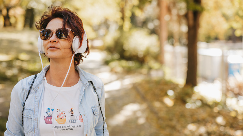 Person listening to headphones in nature environment, outdoor windy concept.