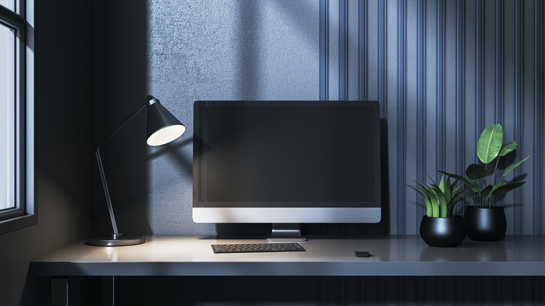 A dark computer monitor next to a small lamp.