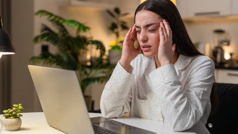 A woman with eye strain in front of a laptop.