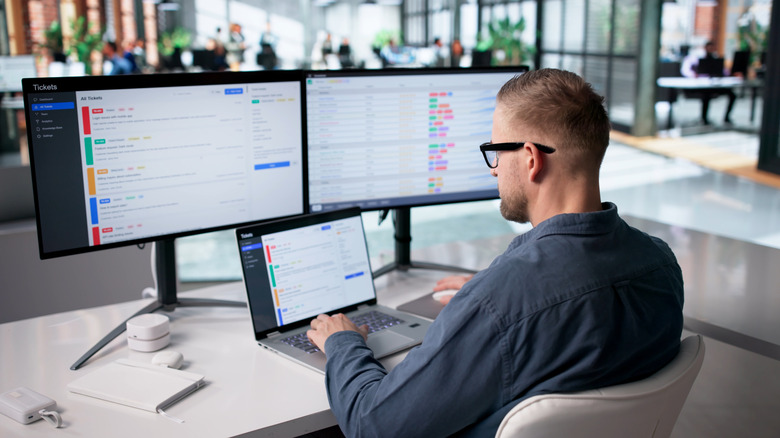 An office worker using multiple high-resolution monitors.