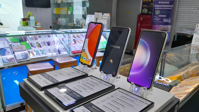 Three Samsung phones sit together on a display inside a mobile phone store