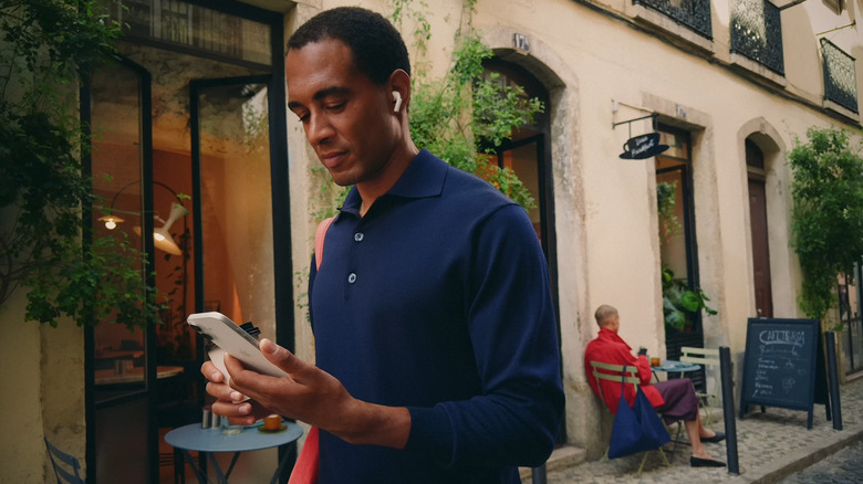 Man holding iPhone while walking and wearing AirPods