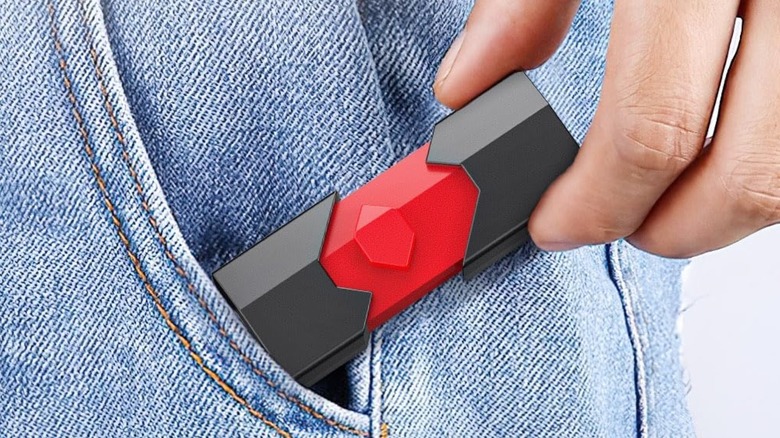 Close-up shot of a left hand placing the Aiibe 128GB Dual Type Flash Drive into a blue jean pocket