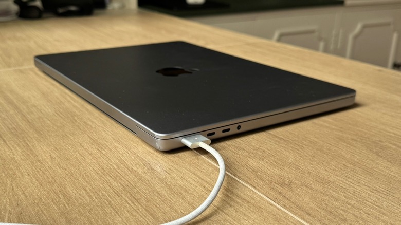 A MacBook Pro being charged with a MagSafe cable on a table