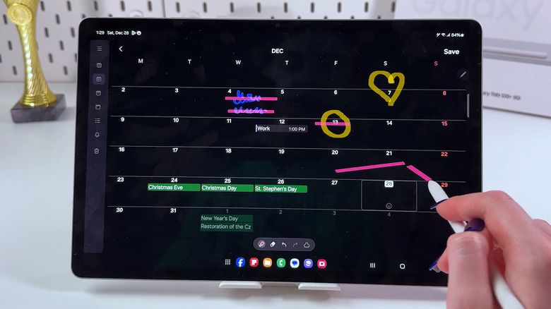Hand using S Pen to draw on Samsung tablet's calendar app