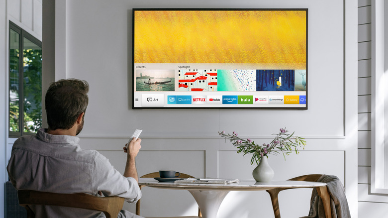 Man using remote with Samsung TV mounted on the wall