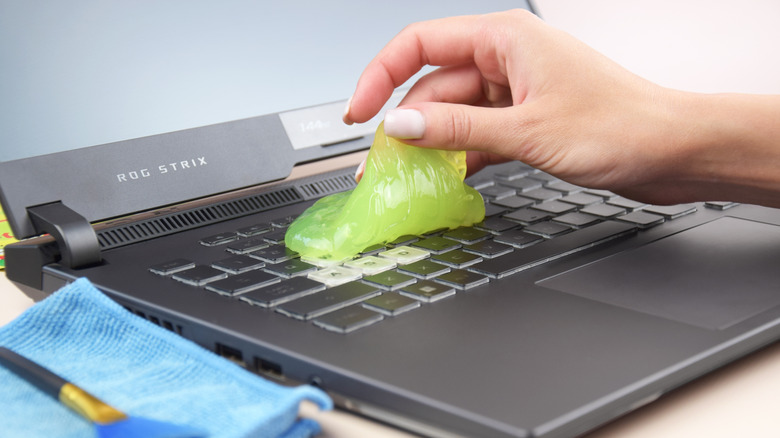 A person cleaning a keyboard with cleaning gel.