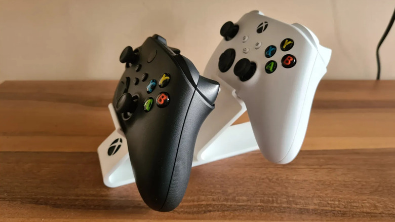 Two Xbox controllers resting on a stand.