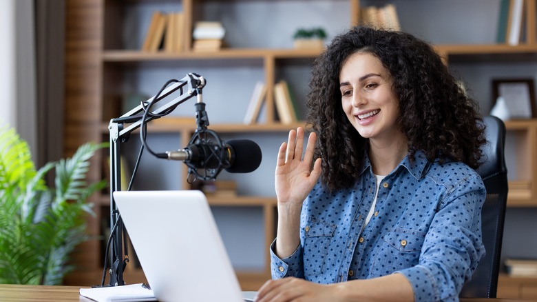 A woman with a microphone looking at a laptop.