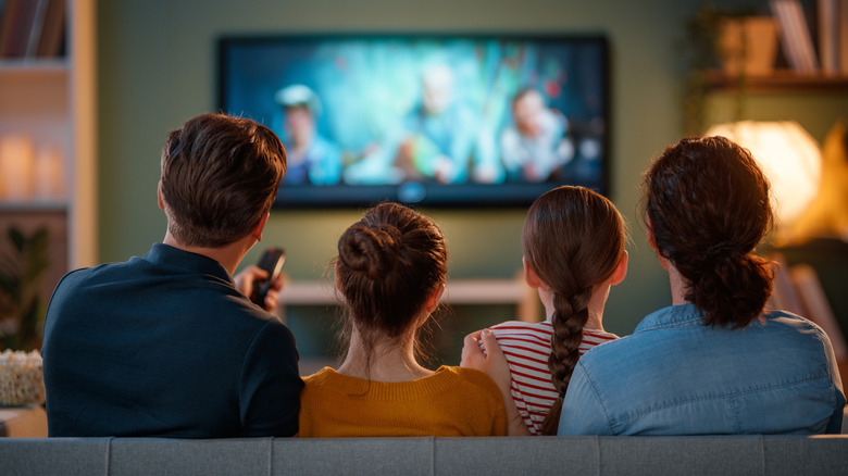 four people watching a tv screen together
