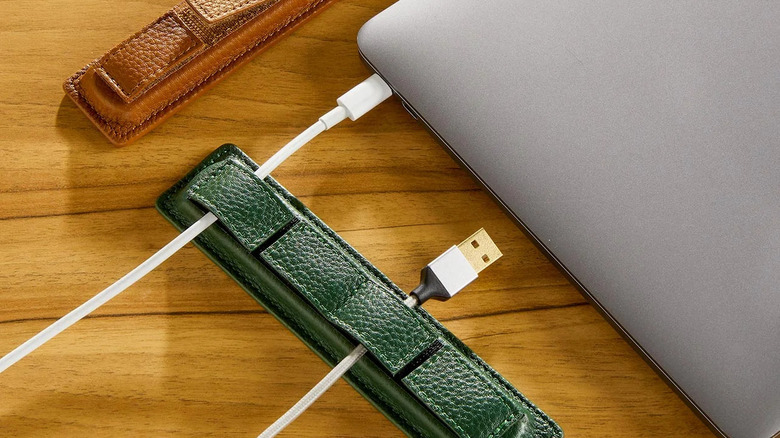 A green Levenger leather strap holding USB-C and USB-A cords in place