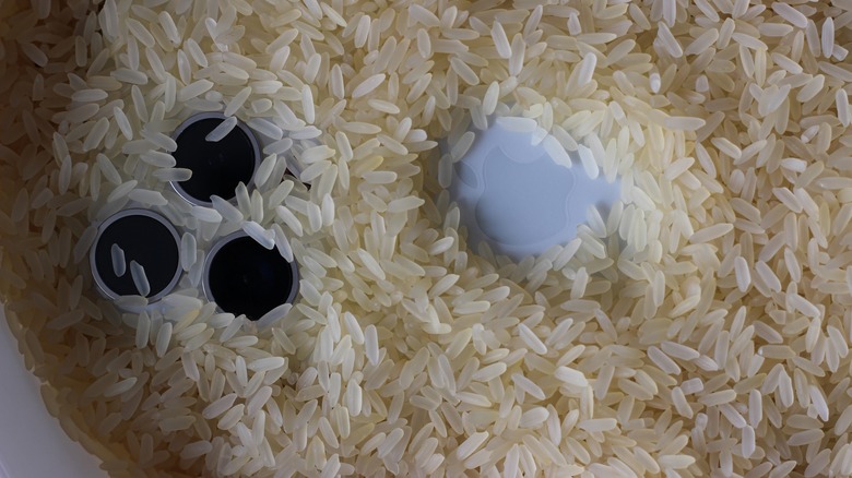 Smartphone completely submerged in rice until only the camera lenses are visible
