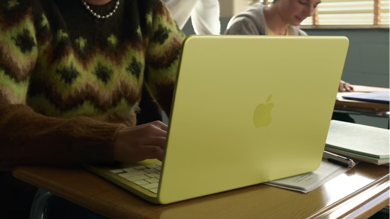 A person using the Apple MacBook Neo (256GB) laptop on a wooden desk.