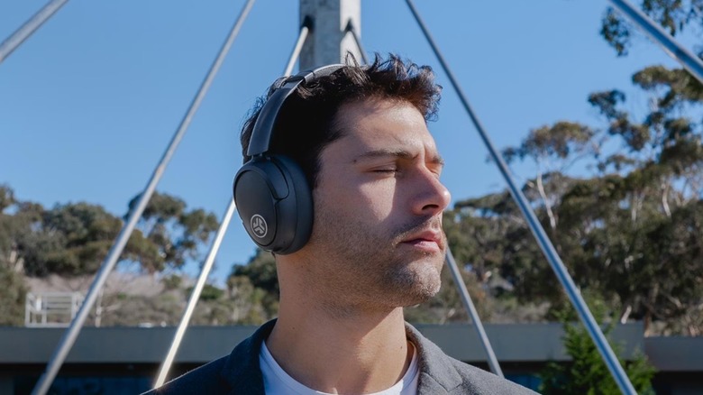 A person wearing the JLab JBuds Lux wireless headphones outdoors.