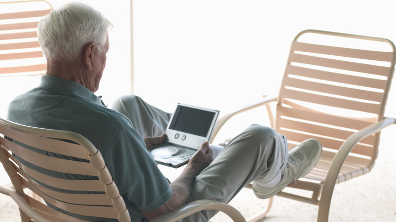 A man sitting on a chair with an old portable DVD player