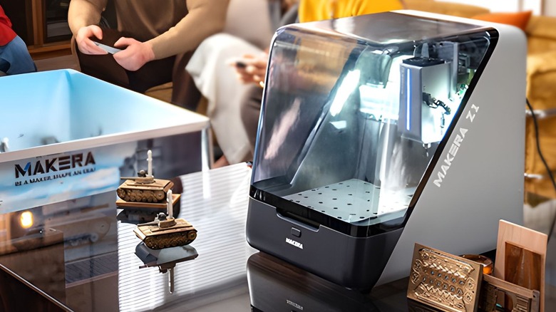 Makera Z1 on a glass worktop surrounded by CNC projects