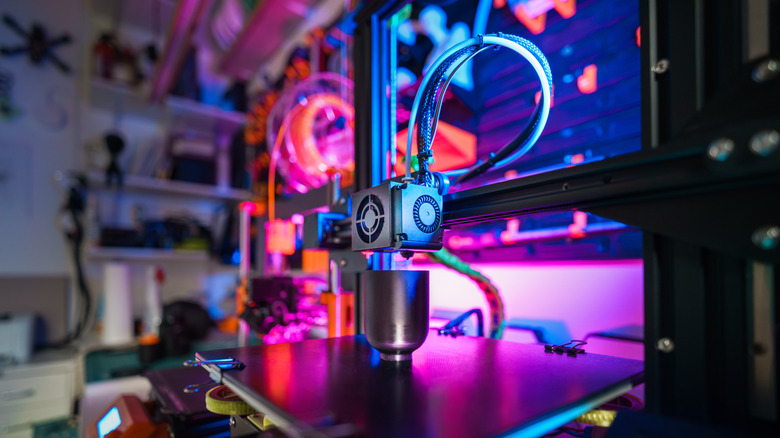 A 3D printer printing a cup lit by RGB lighting.