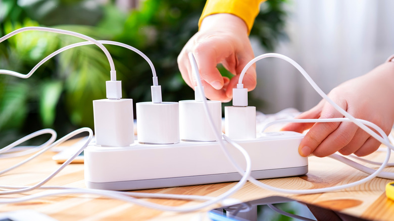 A person plugging multiple chargers into an extension