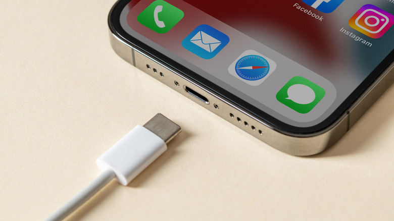 A USB-C cable next to an iPhone's USB-C port