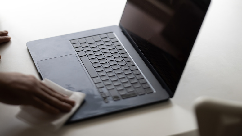 A person cleaning a MacBook.