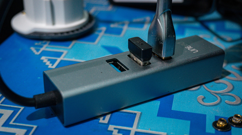 A USB hub with devices plugged in, including a Bluetooth dongle.