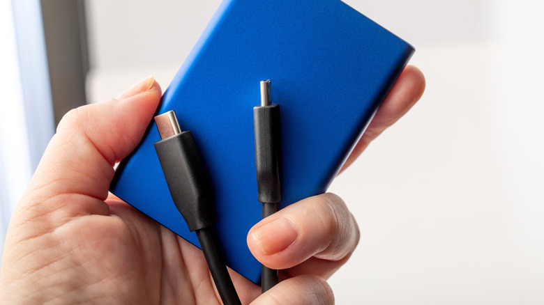 Holding a portable SSD and a USB-C cable