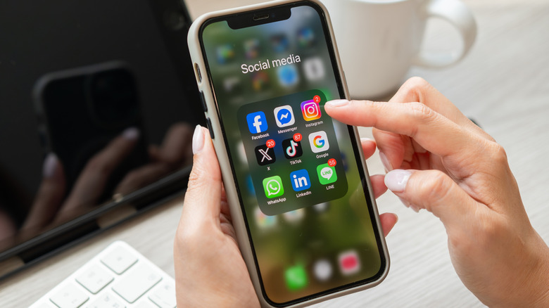 Finger tapping the Instagram icon inside a social media folder on a smartphone screen.