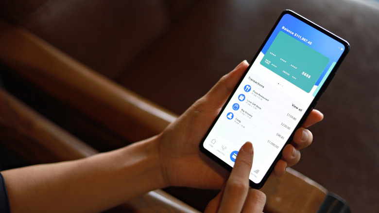 Person using a smartphone banking app showing a balance and recent transactions.
