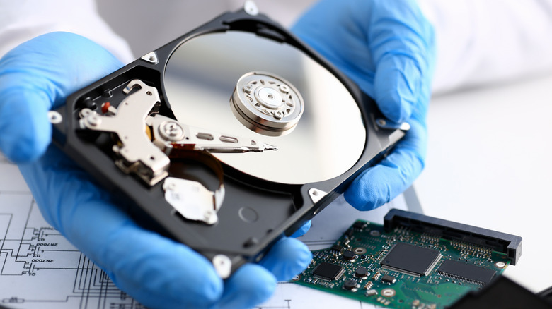 Person with blue gloves holding a hard drive
