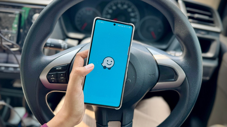 A driver starting the Waze app on an Android phone.