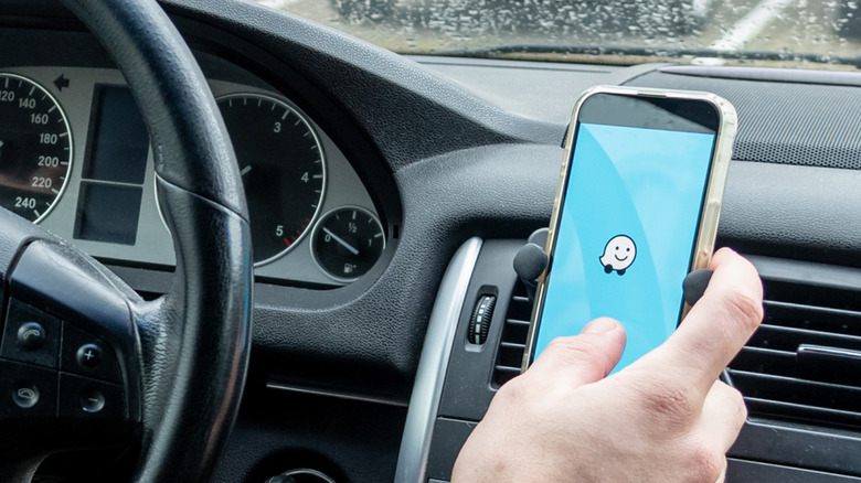 A driver interacting with the Waze app on a mobile phone.