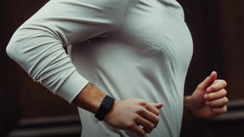 Whoop 5.0 band and fitness tracker on runner's wrist.