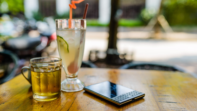 BlackBerry Passport laying on bar table next to beer and mixed drink